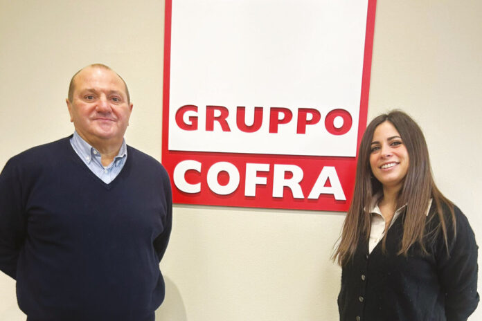 Una foto di due persone davanti a una parete con il logo del Gruppo Cofra