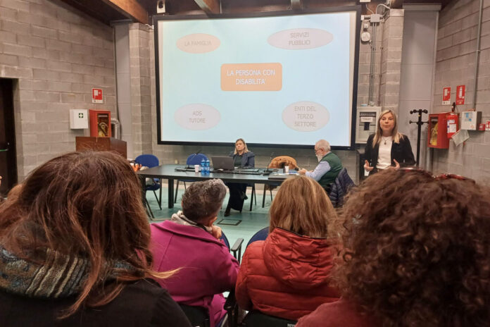 Un'aula con varie persone sedute e la conduttrice dell'incontro