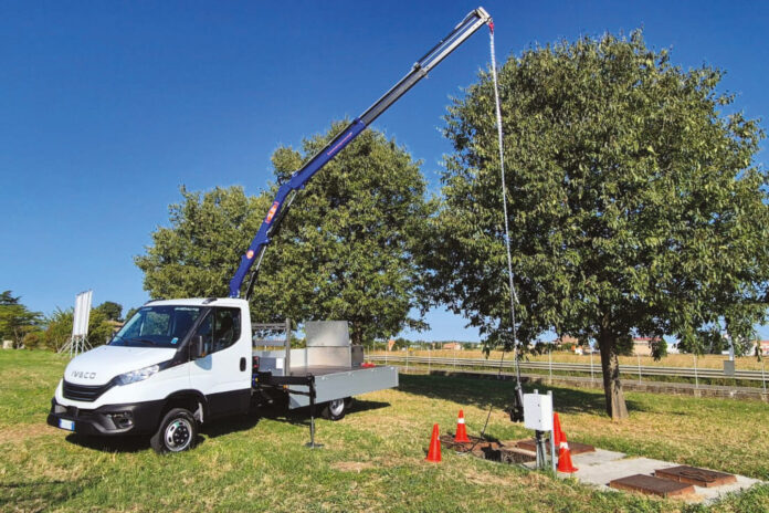 Un nuovo camion gru di Luxco che sta sollevando un pozzetto