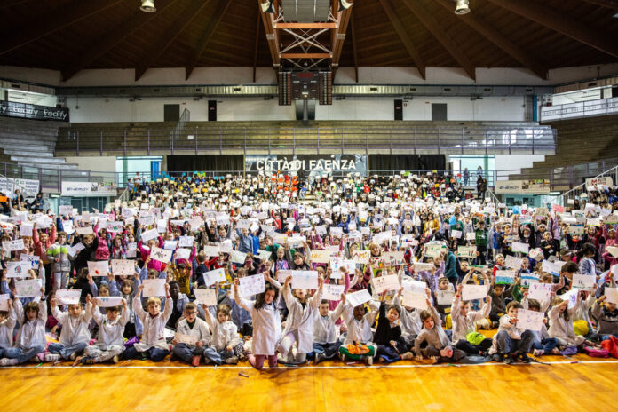 Foto di gruppo con tantissimi bambini che tengono in mano le tovagliette personalizzate da loro